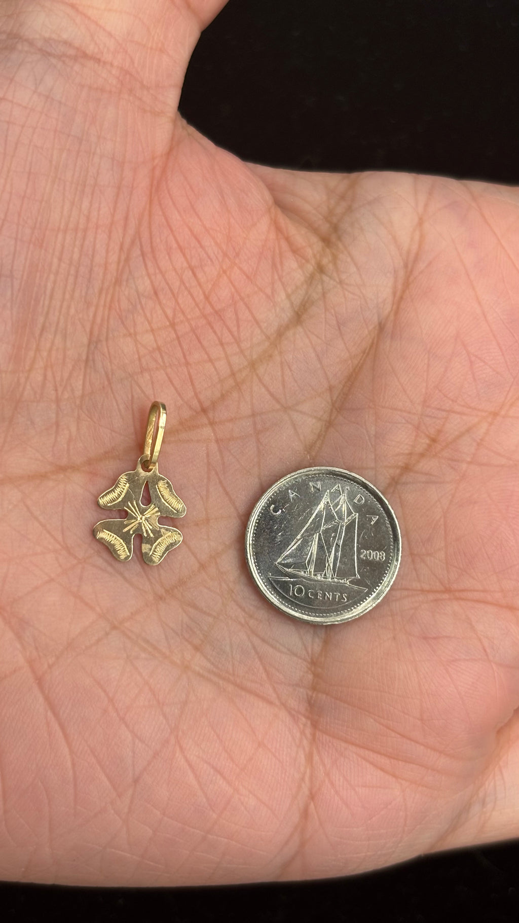 14k solid gold four-leaf clover charm next to 10 cent coin for size reference