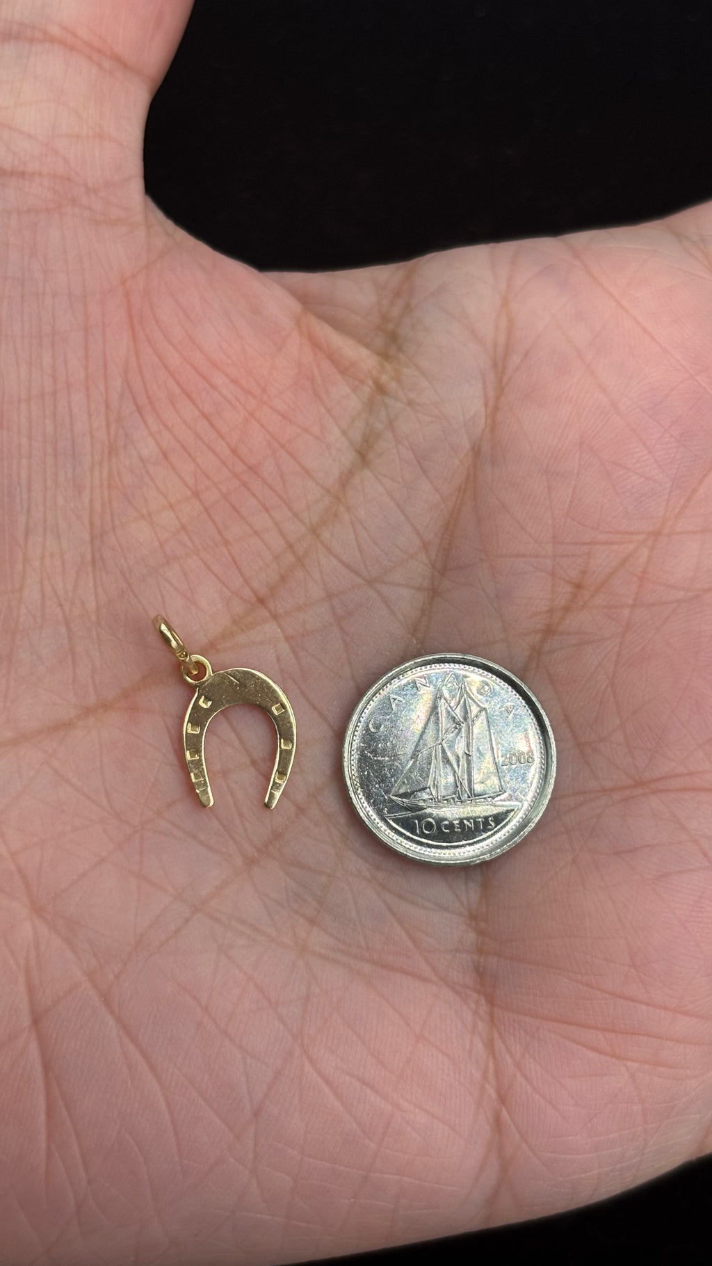 18k solid gold horseshoe charm next to 10 cent coin for size reference