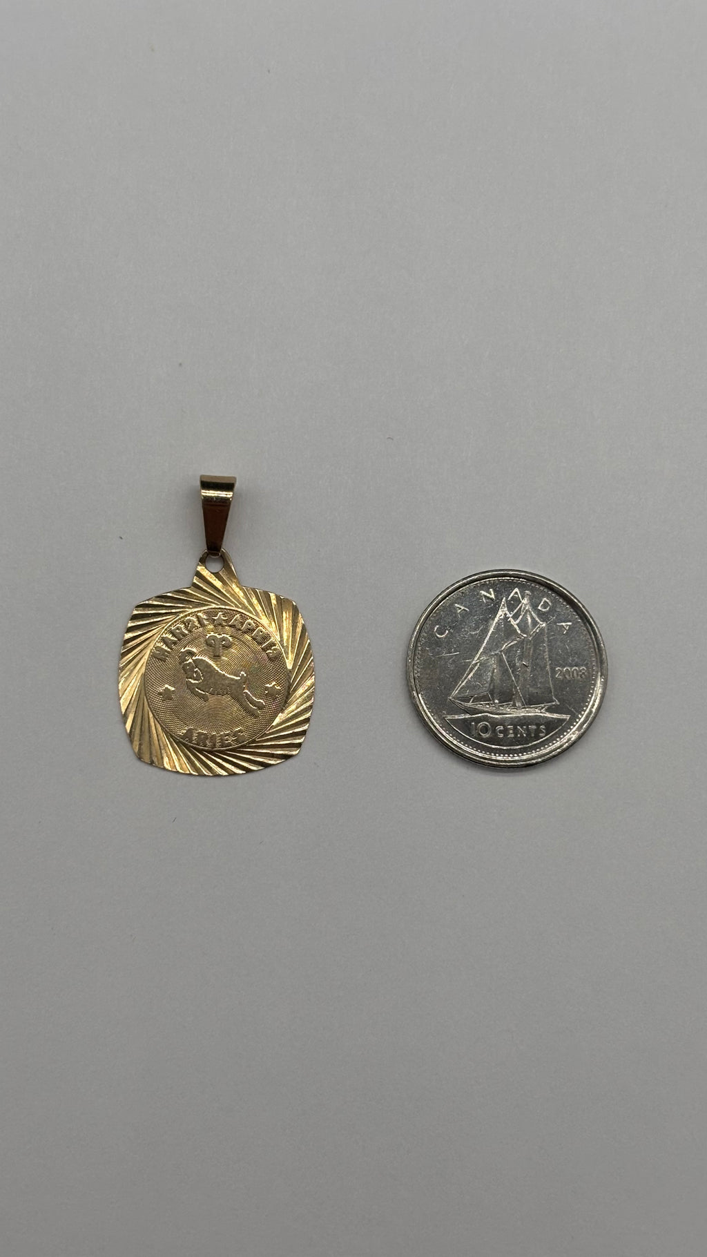 10k square engine turned border Aries charm next to Canadian 10 cent coin for size reference