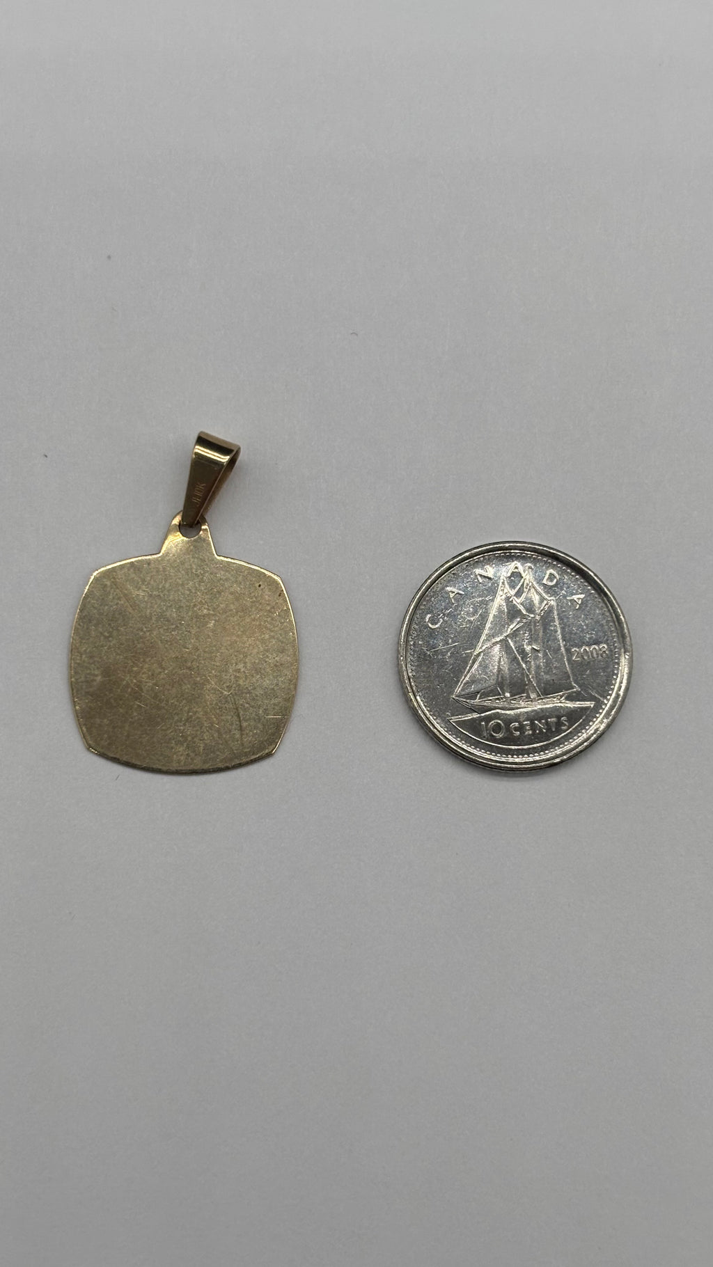 Back of 10k square engine turned border Aries charm next to Canadian 10 cent coin