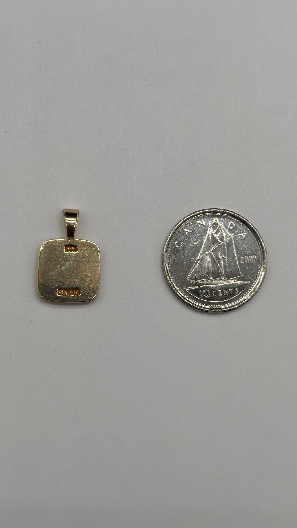 Back of 14k solid gold square Leo pendant with fixed bail next to Canadian 10 cent coin