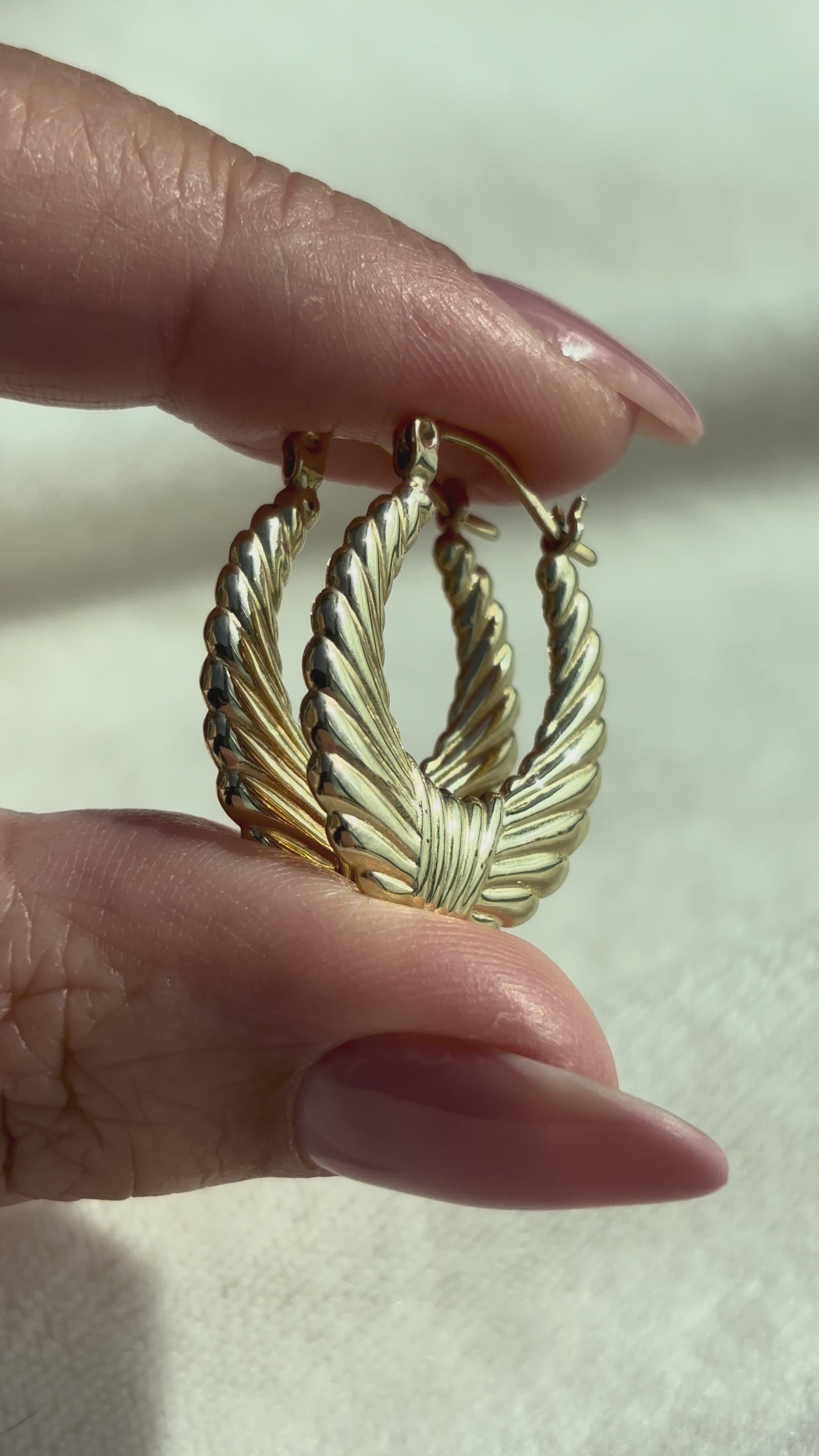 close up video of 14k Solid Gold Woven Effect Hoops moving side to side to show shine, condition, and detail