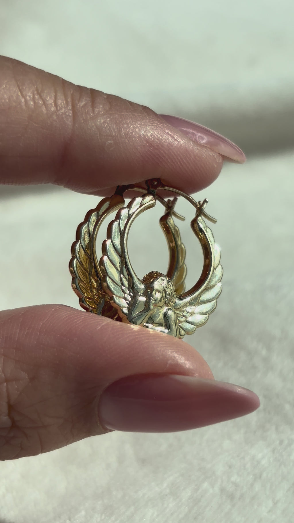 close up video of 14k Solid Gold Sculptural 3D Cherub Hoops moving side to side to show details, shine, and condition