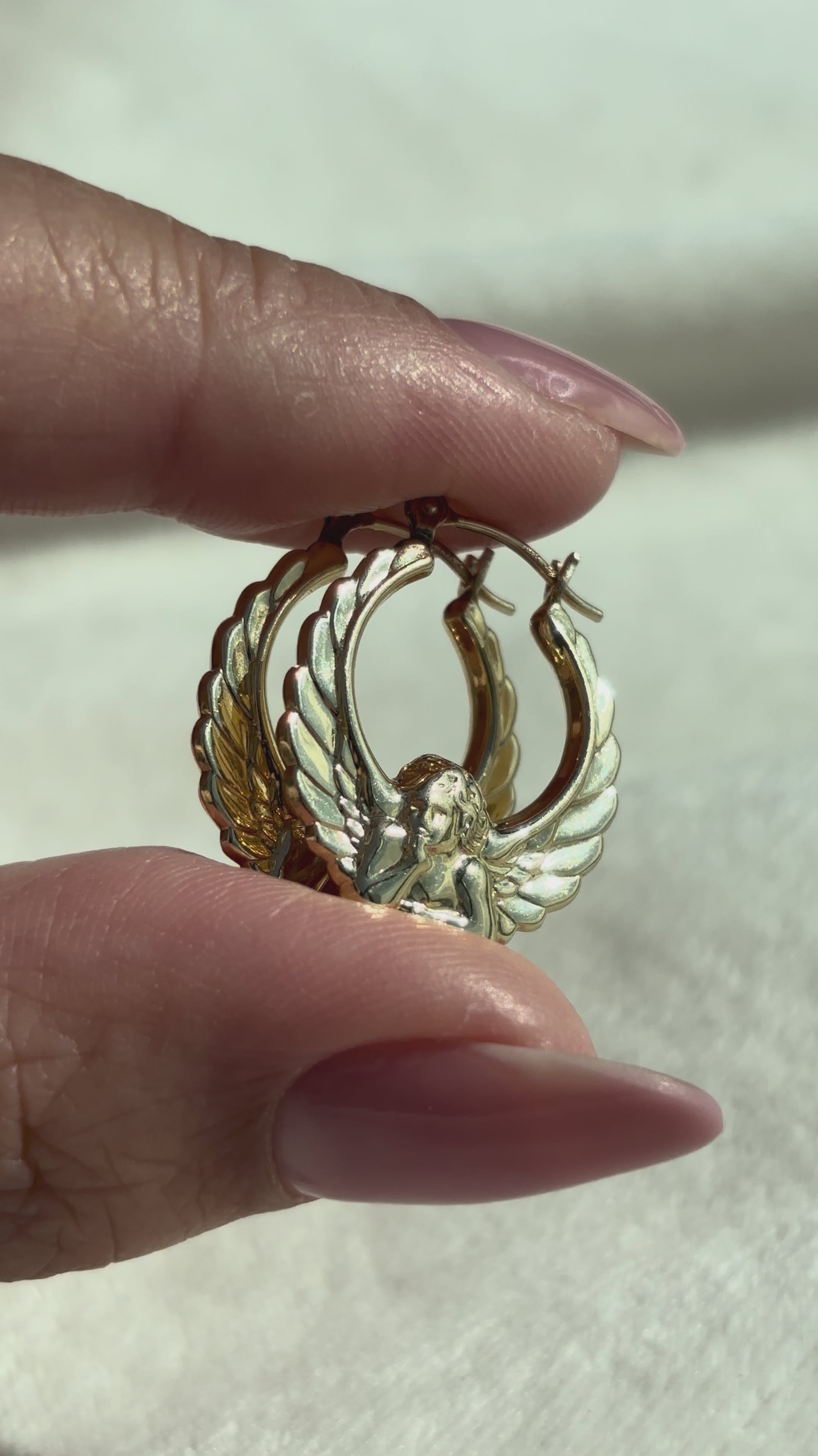 close up video of 14k Solid Gold Sculptural 3D Cherub Hoops moving side to side to show details, shine, and condition